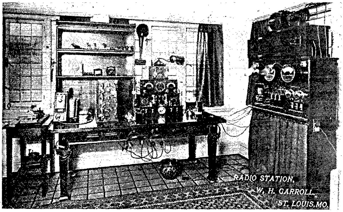 Historische Zeitschriftenabbildung einer Amateurfunkstation von 1915: Holztisch mit Spulen, Funkenstrecke und Messgeräten, rechts ein hohes Gerätegestell